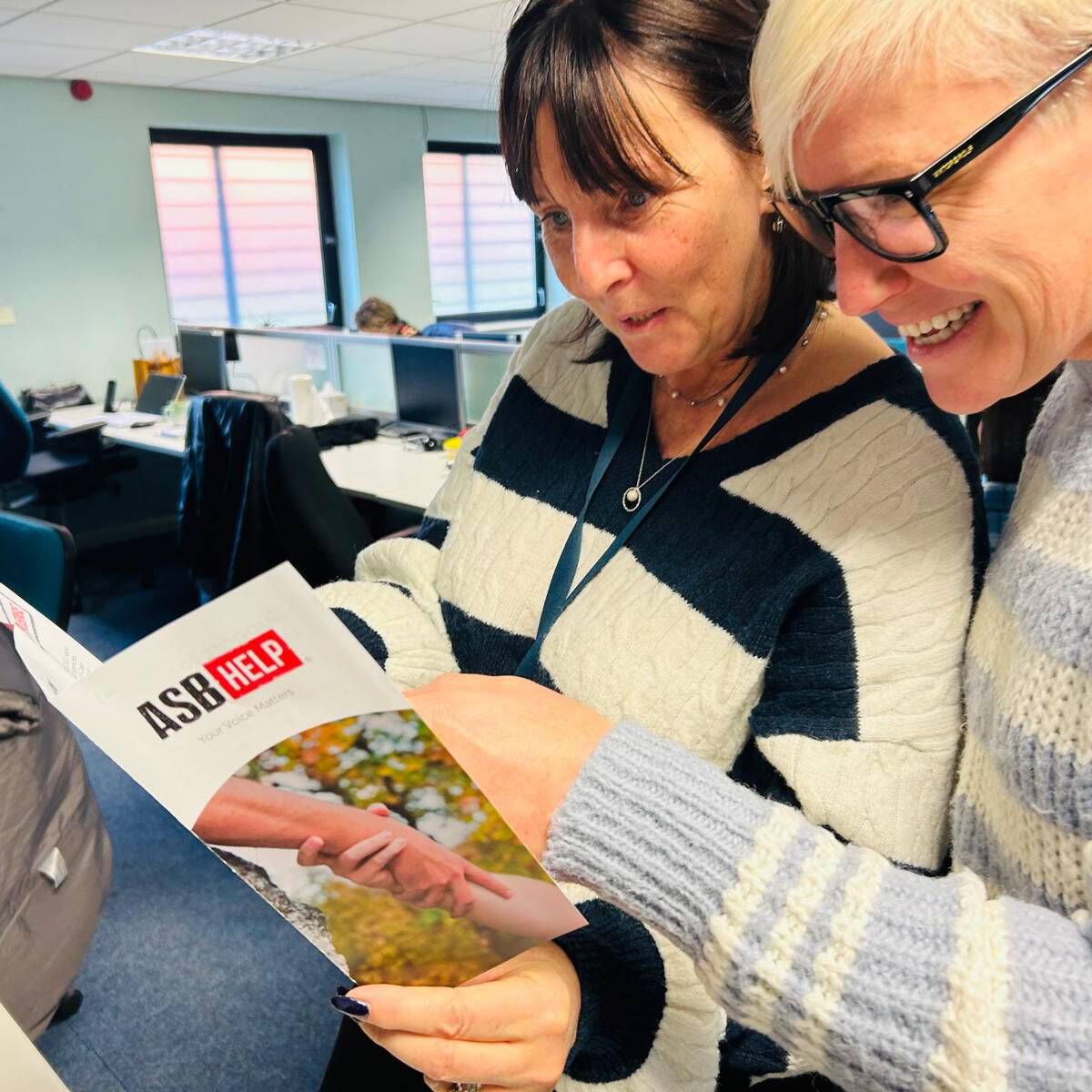 Two people reading the ASB Help leaflet.
